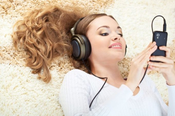 16466483 - smiling woman lying on carpet and listening to music