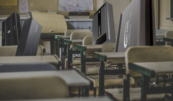 Various amplifiers sitting in chairs at school desks in a classroom