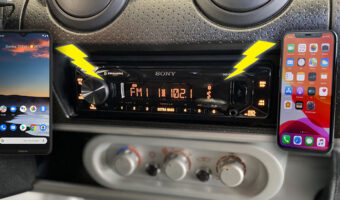 An old time car radio installed and two cell phones with lighting bolts connecting them to the radio system